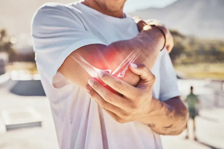 A person in a white T-shirt holds their elbow, with a digital effect highlighting pain or injury in the joint area.