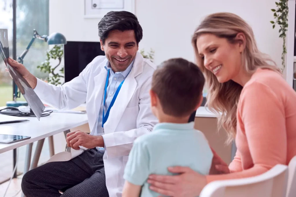 A friendly doctor showing X-ray results to a smiling mother and her child during a family consultation at a clinic