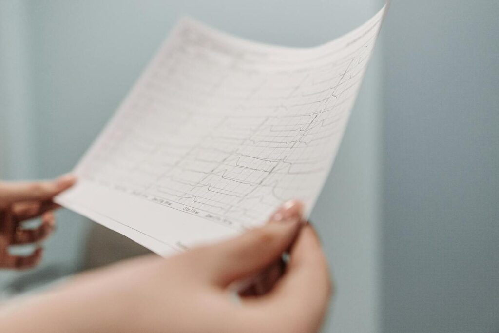 A person holds and examines a printed medical chart with multiple lines and graphs, likely showing results from a diagnostic test.