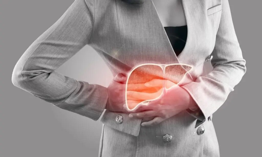 A person in a grey suit holds their right side in pain; a graphic of a liver is overlaid on the area they are touching.